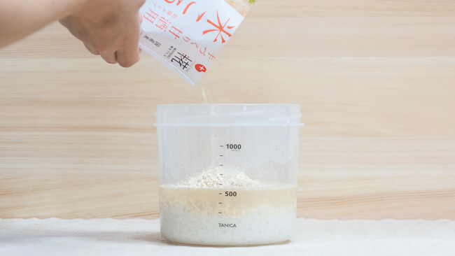 プラスチック容器に米麹を入れている